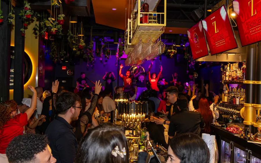 A packed room at a CLOO Entertainment night: live band on stage and the crowd with their hands up.